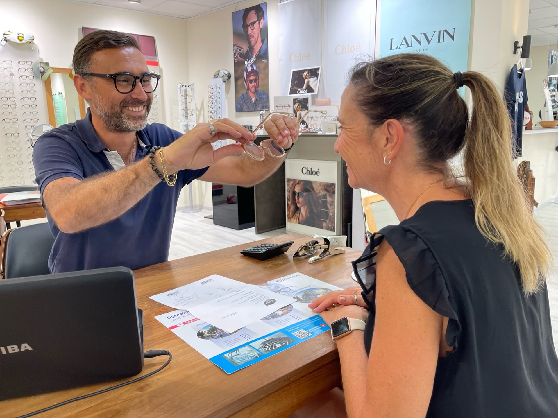Un opticien fait essayer des lunettes à une cliente